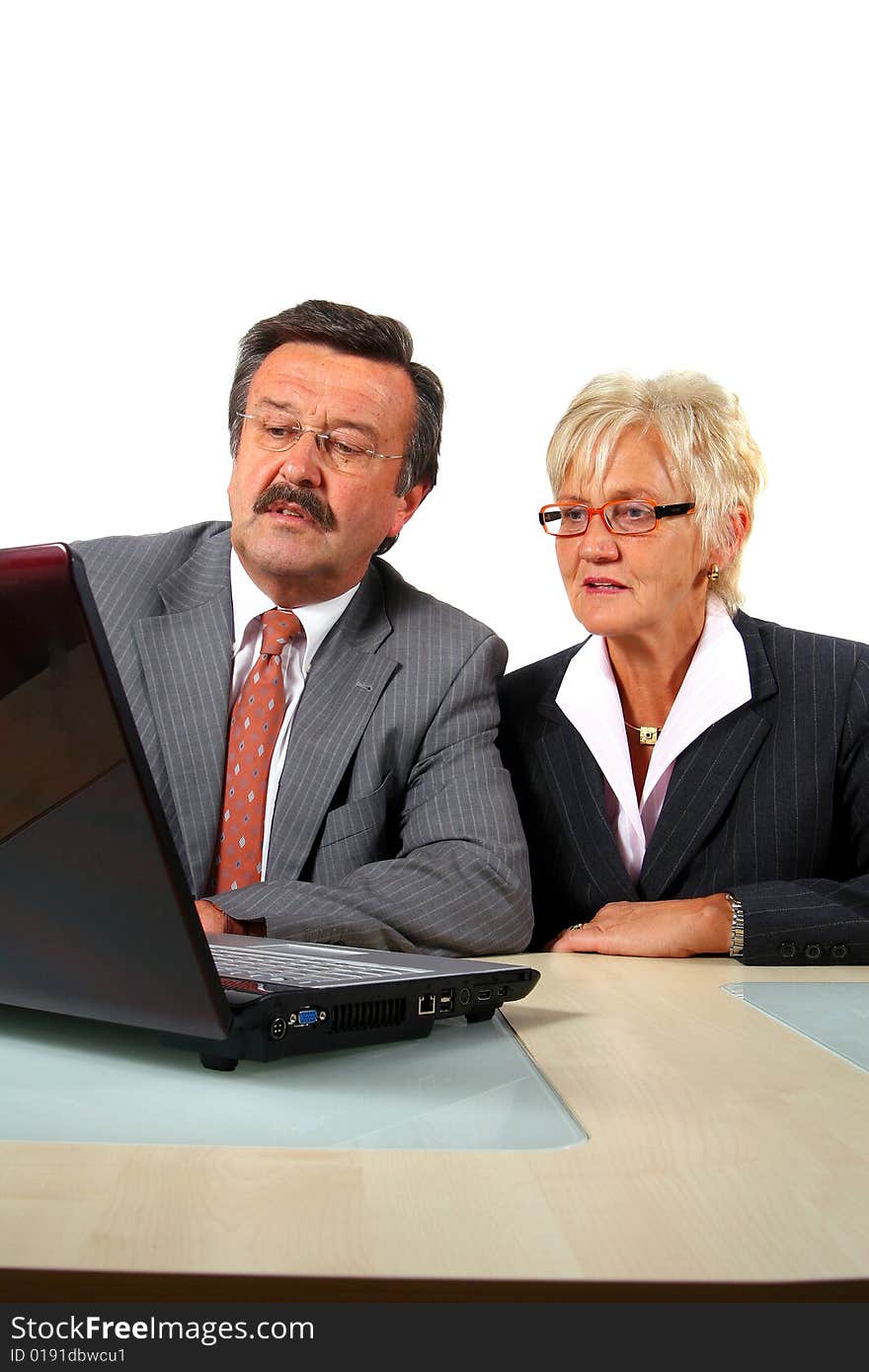 A senior businesswoman in her fitifties is working on a laptopt in an office. Isolated over white. A senior businesswoman in her fitifties is working on a laptopt in an office. Isolated over white.