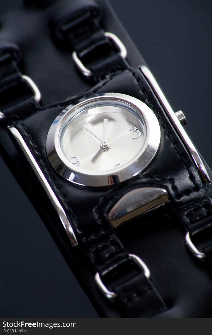 Little wristwatch with black strap on dark background