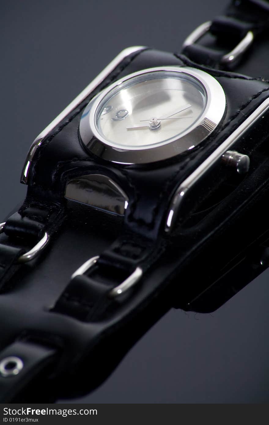 Little wristwatch with black strap on dark background