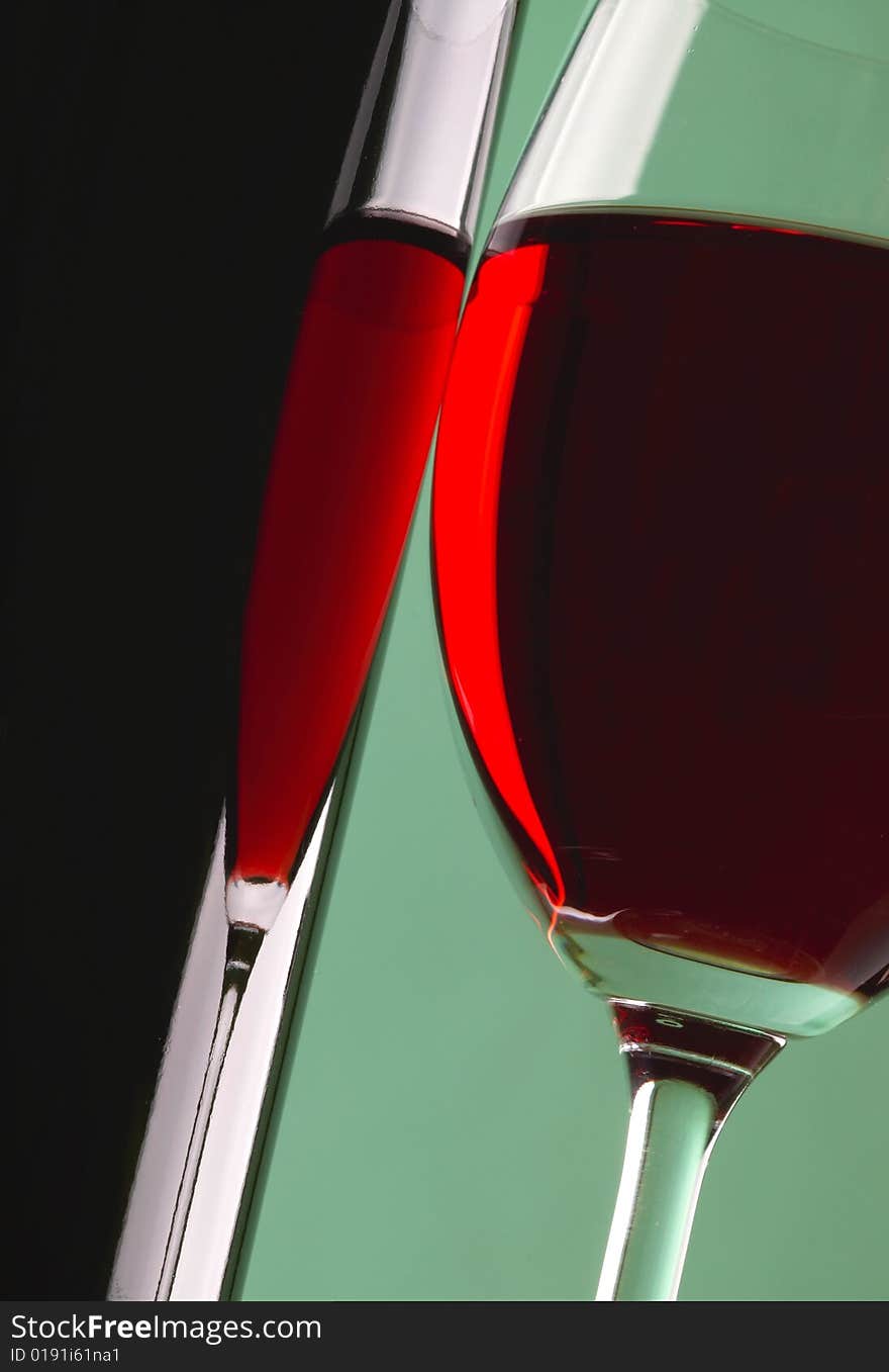 Glass and bottle of red wine on green background