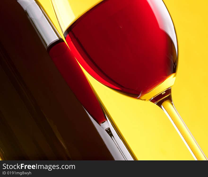 Glass and bottle of red wine on yellow background