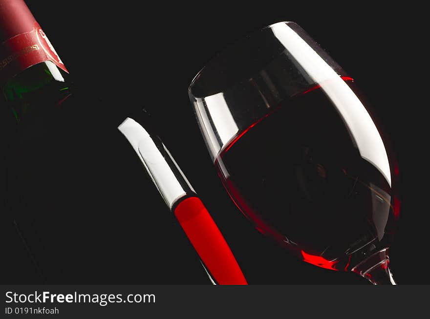 Glass and bottle of red wine on black