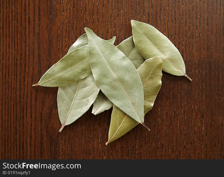 A small group of dry bay leaves on a wood background