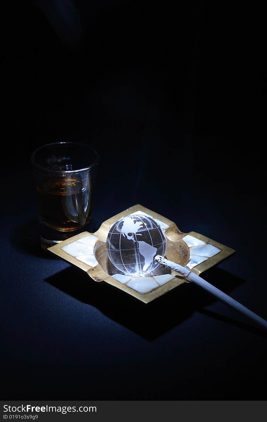 Glass of whiskey near old ashtray with glassy globe and cigarette. Glass of whiskey near old ashtray with glassy globe and cigarette