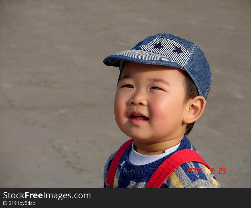 A cute chinese boy staning still and looking for kites flying in the sky in a sunny day. A cute chinese boy staning still and looking for kites flying in the sky in a sunny day