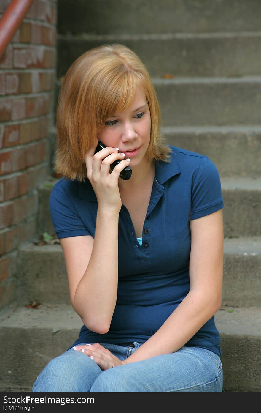 A teenage girl chats happily on her cell phone on the outdoor stairs of a college campus with space for copy. Technology, communications, lifestyle concept. A teenage girl chats happily on her cell phone on the outdoor stairs of a college campus with space for copy. Technology, communications, lifestyle concept.