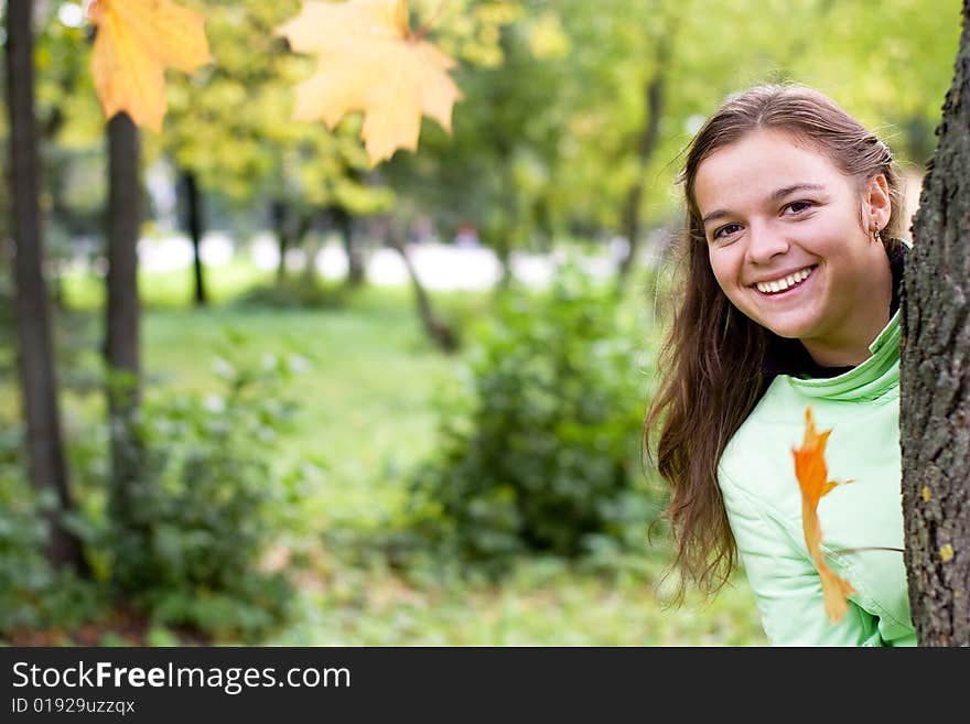 Smiling girl and falling maple leaves in autumn