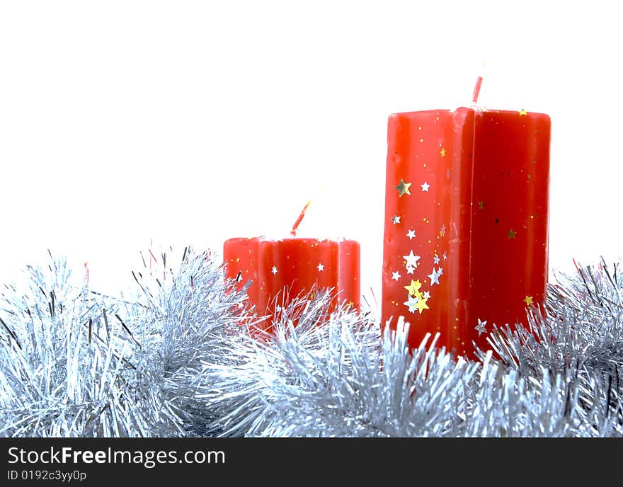 Two red candles decorated with stars and tinsel isolated over white