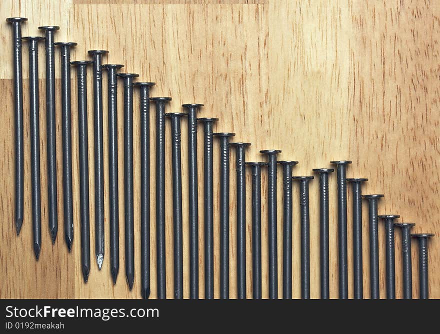 Declining Graph of Nails on a Wood Background.