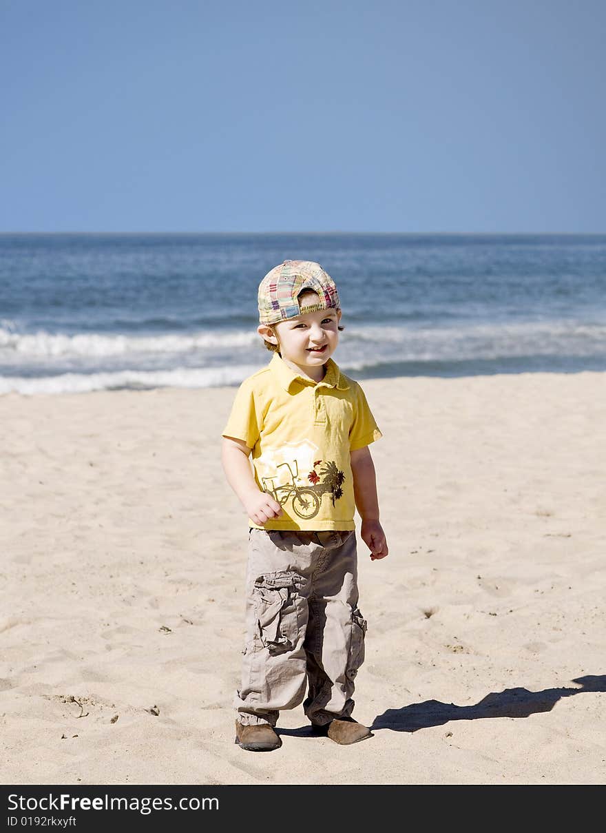 Little boy standing on the beach and smiling