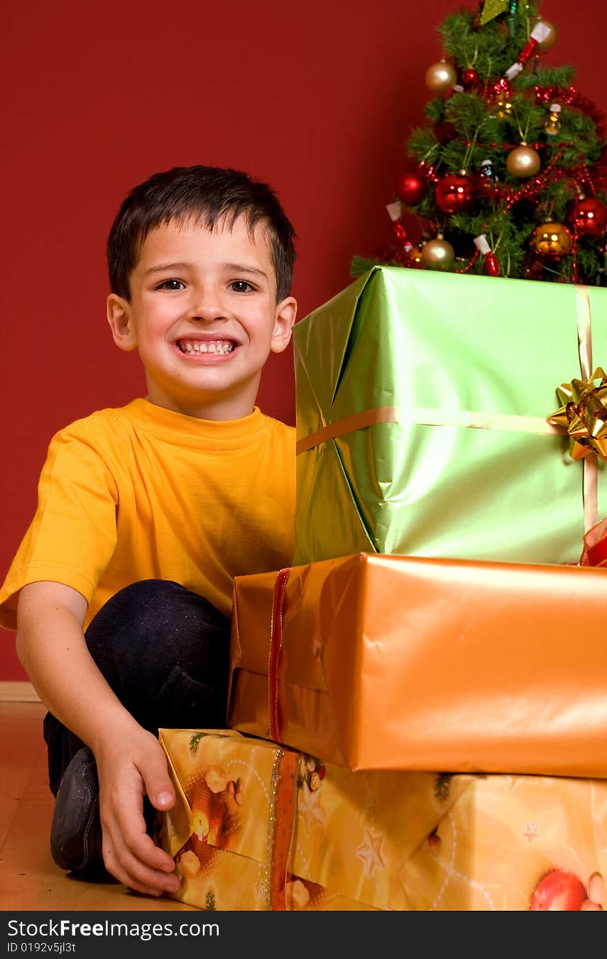 Boy in jeans and yellow top carrying three gifts tied with colourful ribbons. Boy in jeans and yellow top carrying three gifts tied with colourful ribbons..