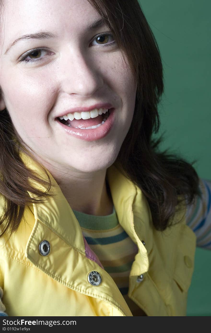 Young woman standing against a green background wearing a yellow vest. Young woman standing against a green background wearing a yellow vest