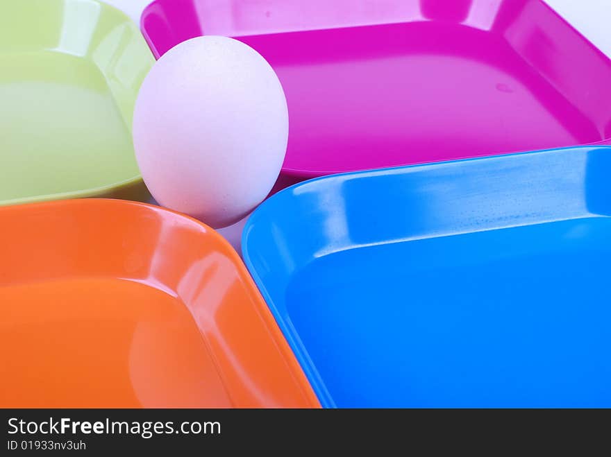 White egg among colorful plates. White egg among colorful plates