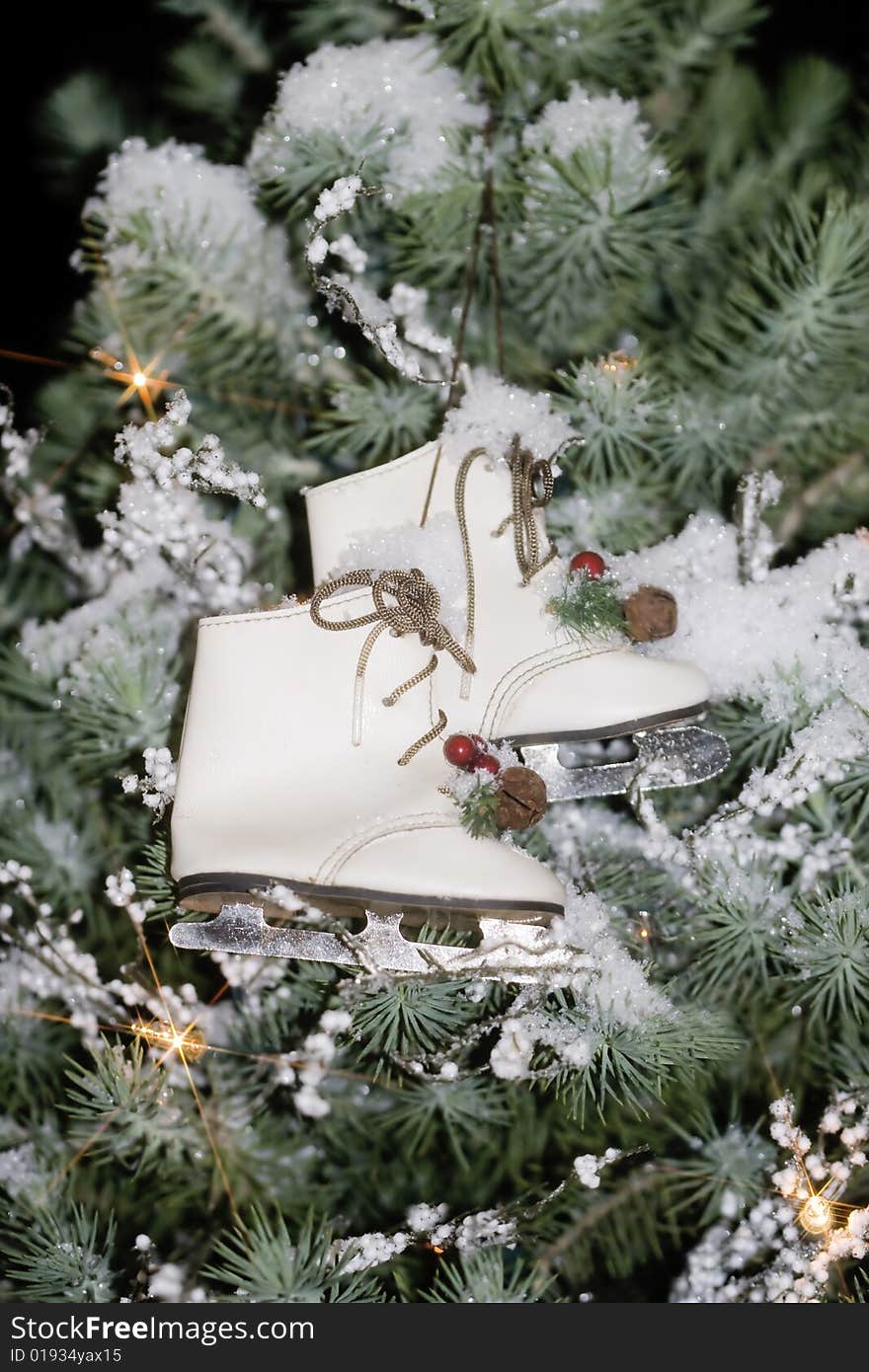 Miniature vintage ice skate ornaments hanging in tree with snow and lights. Miniature vintage ice skate ornaments hanging in tree with snow and lights