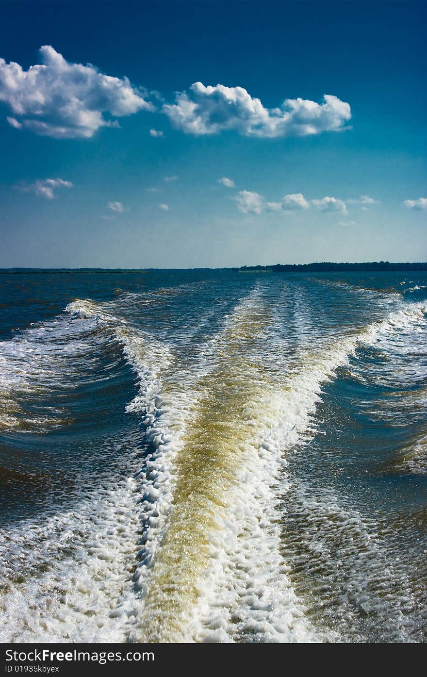 Wake of a speed boat against the blue sky