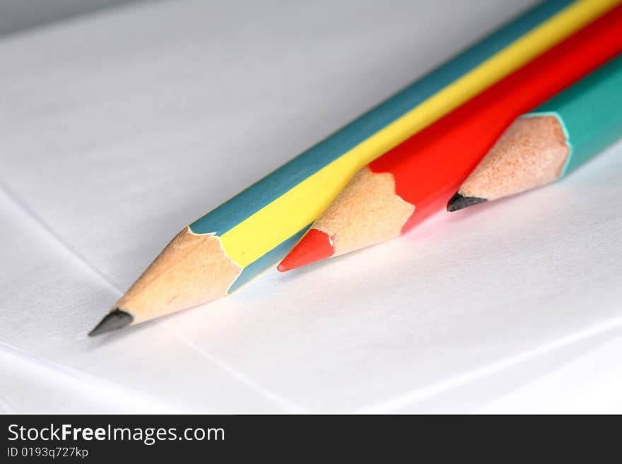 Closeup image of three pencils laying on white paper