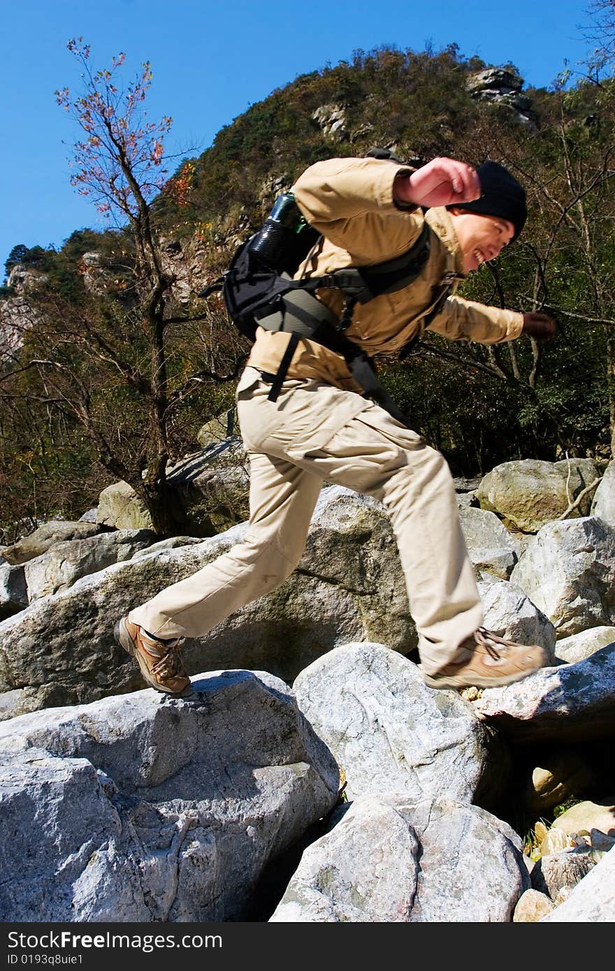 Hiker jumping from rock to rock while crossing river. Hiker jumping from rock to rock while crossing river.