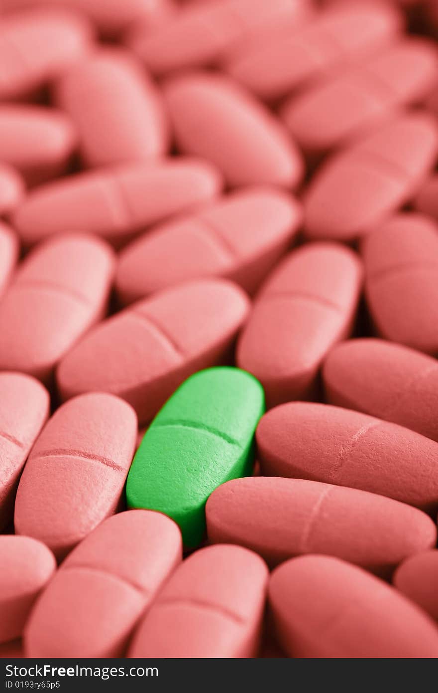 Macro of red prescription pills with one green pill. Macro of red prescription pills with one green pill