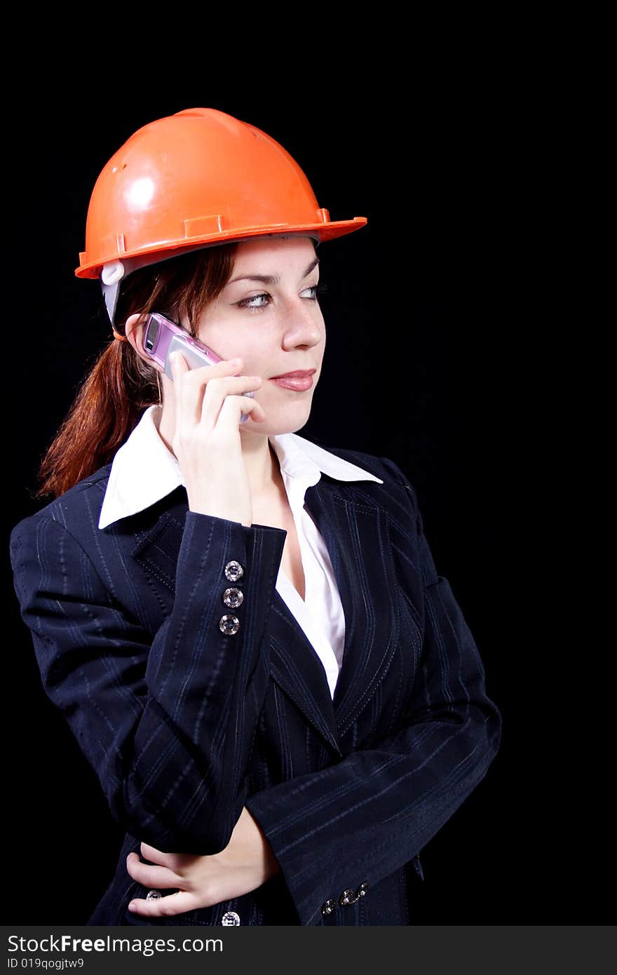 Girl in a business suit with phone and in a helmet on a black background. Girl in a business suit with phone and in a helmet on a black background