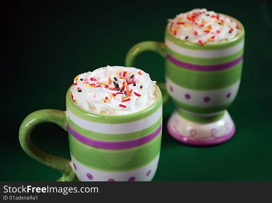 Colorful striped mugs of hot cocoa and whipped cream