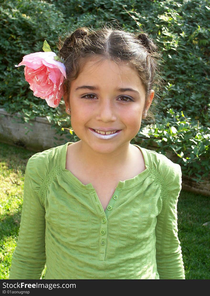 Cute little girl playing dress up with a flower in her hair and lipstick on