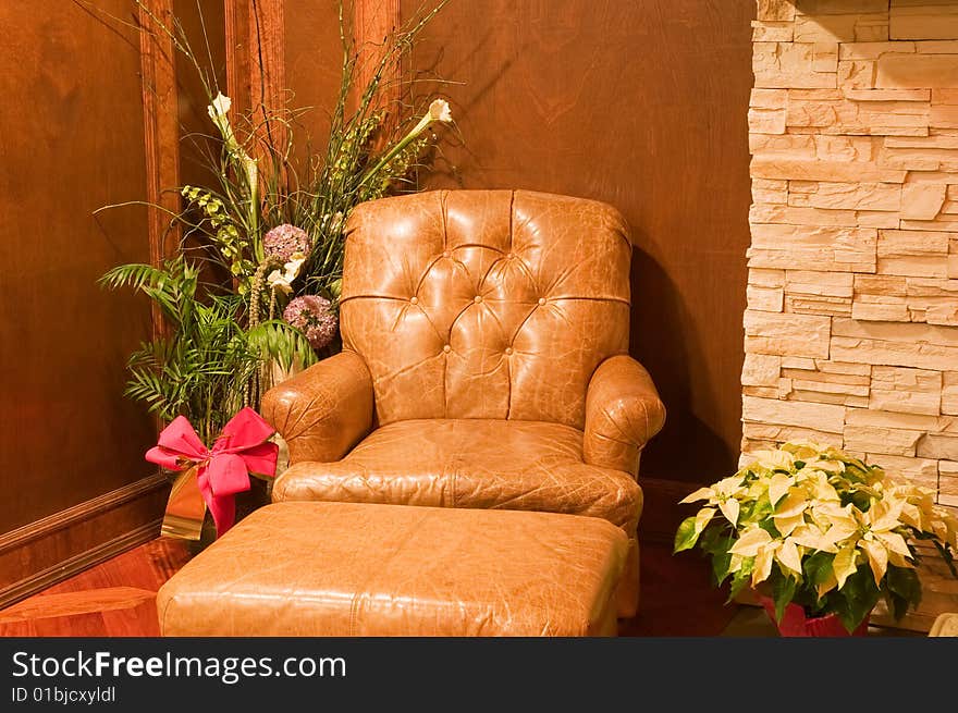 A view of a comfortable, stuffed leather chair next to a decorative green plant in a living room corner. A view of a comfortable, stuffed leather chair next to a decorative green plant in a living room corner.