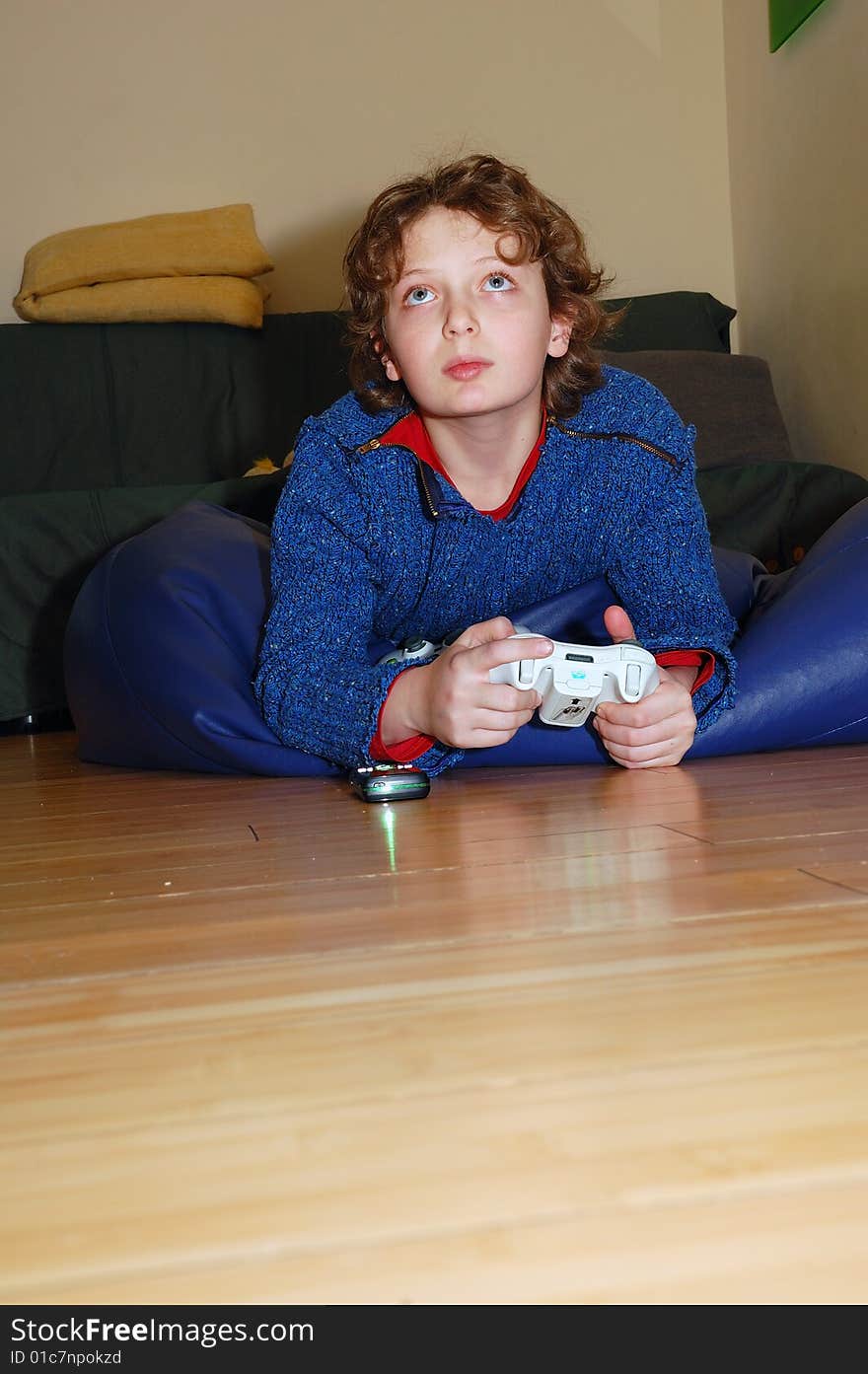 Blond boy lying on the floor and playing his vidoe game. Blond boy lying on the floor and playing his vidoe game