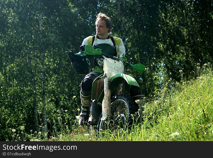 Handsome man sitting on motocross. Spring, full of green colour background. Handsome man sitting on motocross. Spring, full of green colour background.