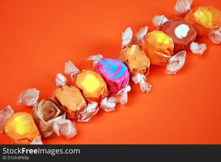 Colorful wrapped taffy candy on orange background