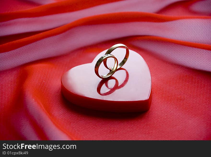 Rings on a small box as a heart  on a red background. Rings on a small box as a heart  on a red background