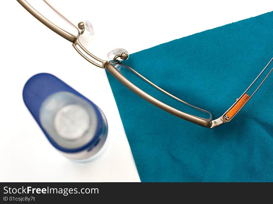 Glasses, cleaning cloth and spray cleaner on white background - vision care