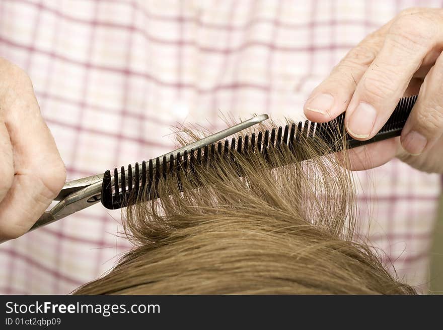 Light brown hair trimmed on black comb with silver scissors. Light brown hair trimmed on black comb with silver scissors