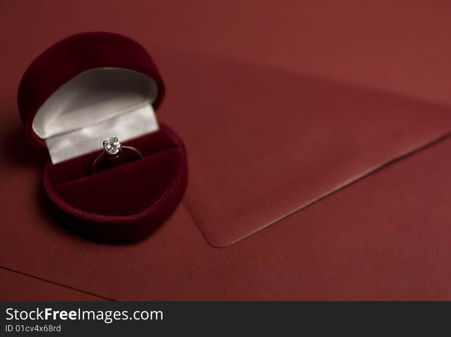 A diamond ring in a deep purple velvet box shaped as a heart lying on an envelope. A diamond ring in a deep purple velvet box shaped as a heart lying on an envelope.