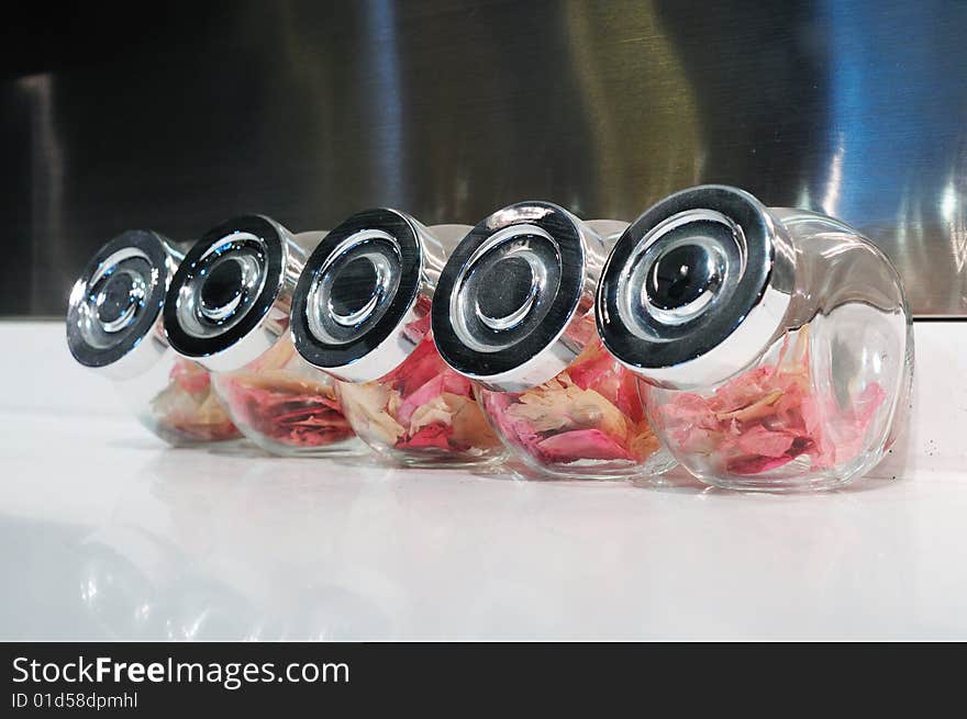 Five glass bottles filled with rose petal on white table. Five glass bottles filled with rose petal on white table