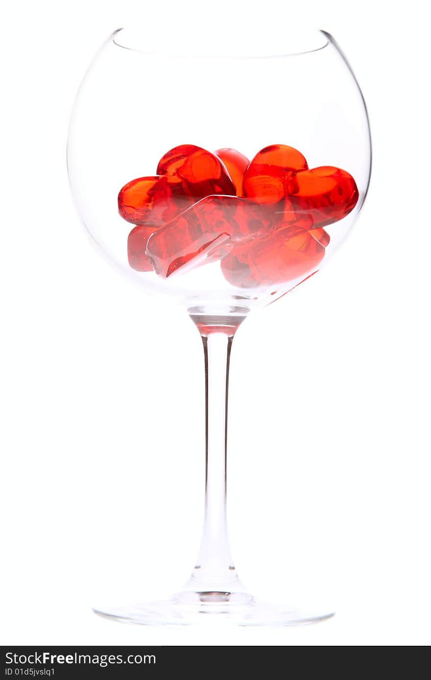 Red jelly hearts in wine glass over white background