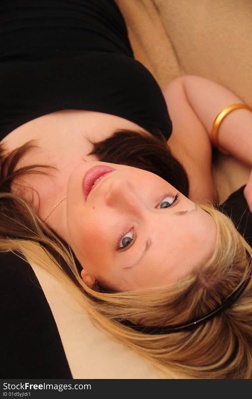 Young blond haired women lying back looking at camera with head tilted with blue eyes. Young blond haired women lying back looking at camera with head tilted with blue eyes.