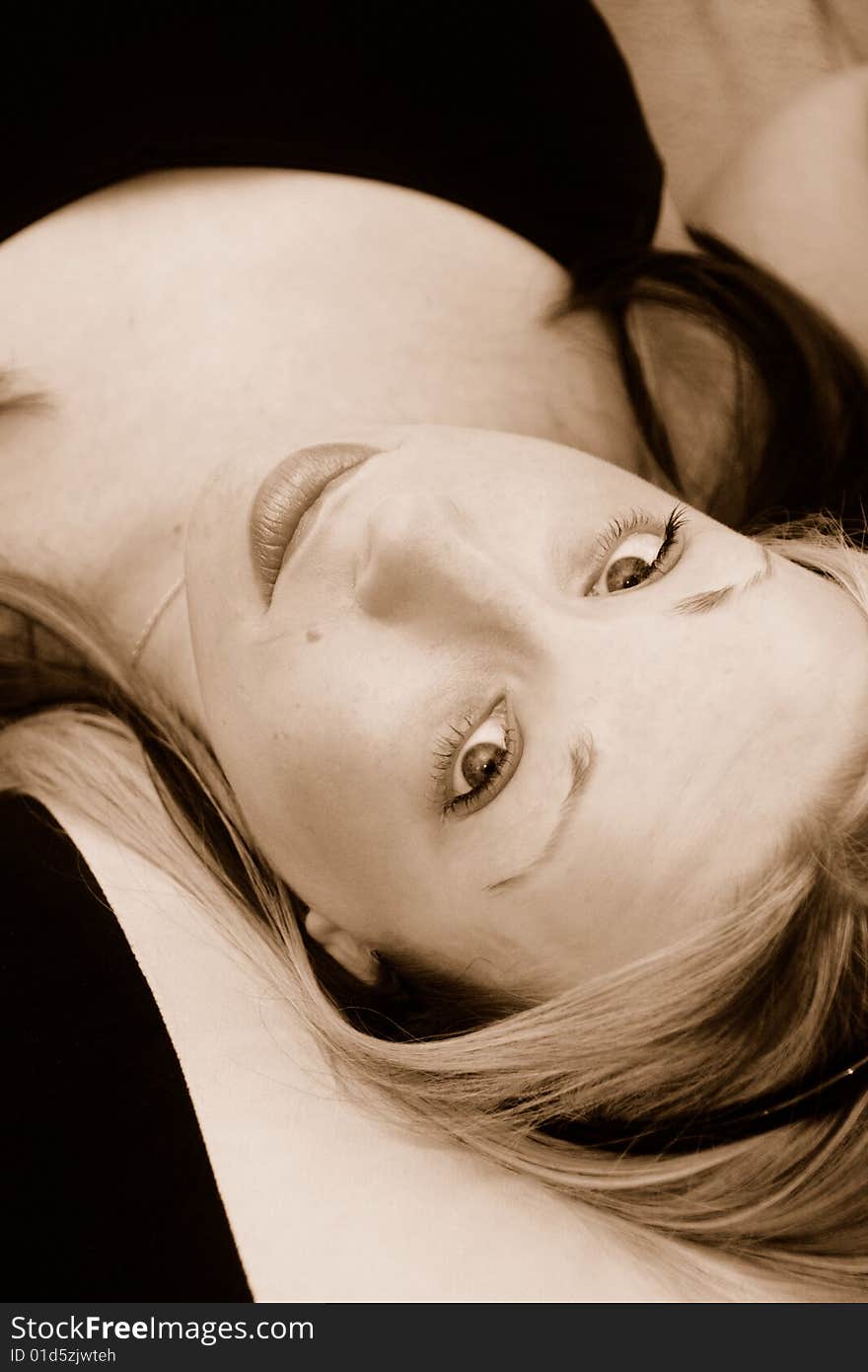 Young blond haired women lying back looking at camera head tilted in sepia tint. Young blond haired women lying back looking at camera head tilted in sepia tint