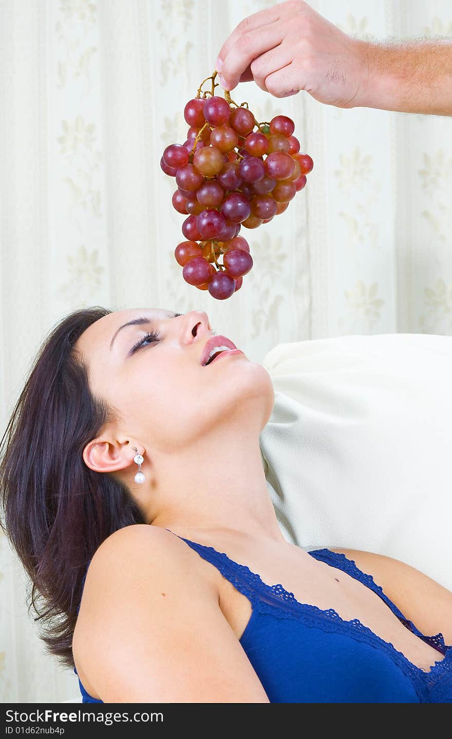 Close up portrait of nice young brunette getting tempted with grape. Close up portrait of nice young brunette getting tempted with grape