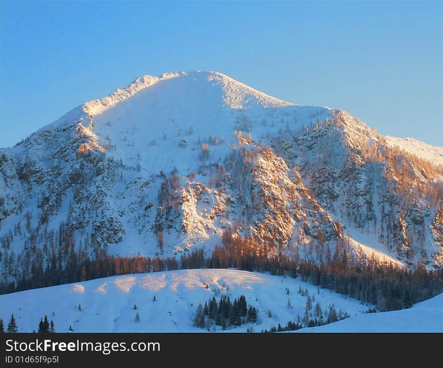 A snowy mountain glowing in the winter sun. A snowy mountain glowing in the winter sun