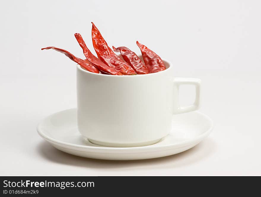 Macro shot of red hot chili peppers with white cup plate. Macro shot of red hot chili peppers with white cup plate