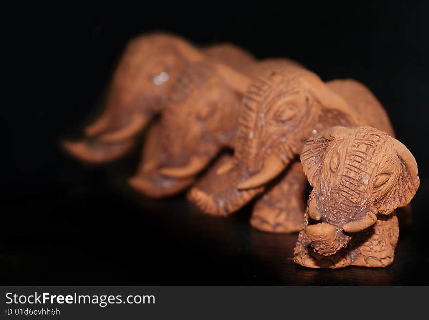 4 Brown clay elephants on a black background