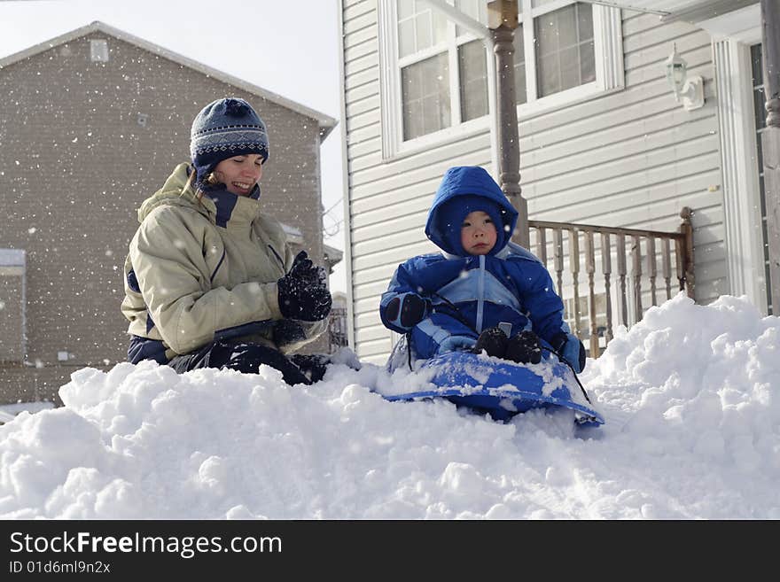 A mother watching her son on a sled on freshly fallen snow. A mother watching her son on a sled on freshly fallen snow.