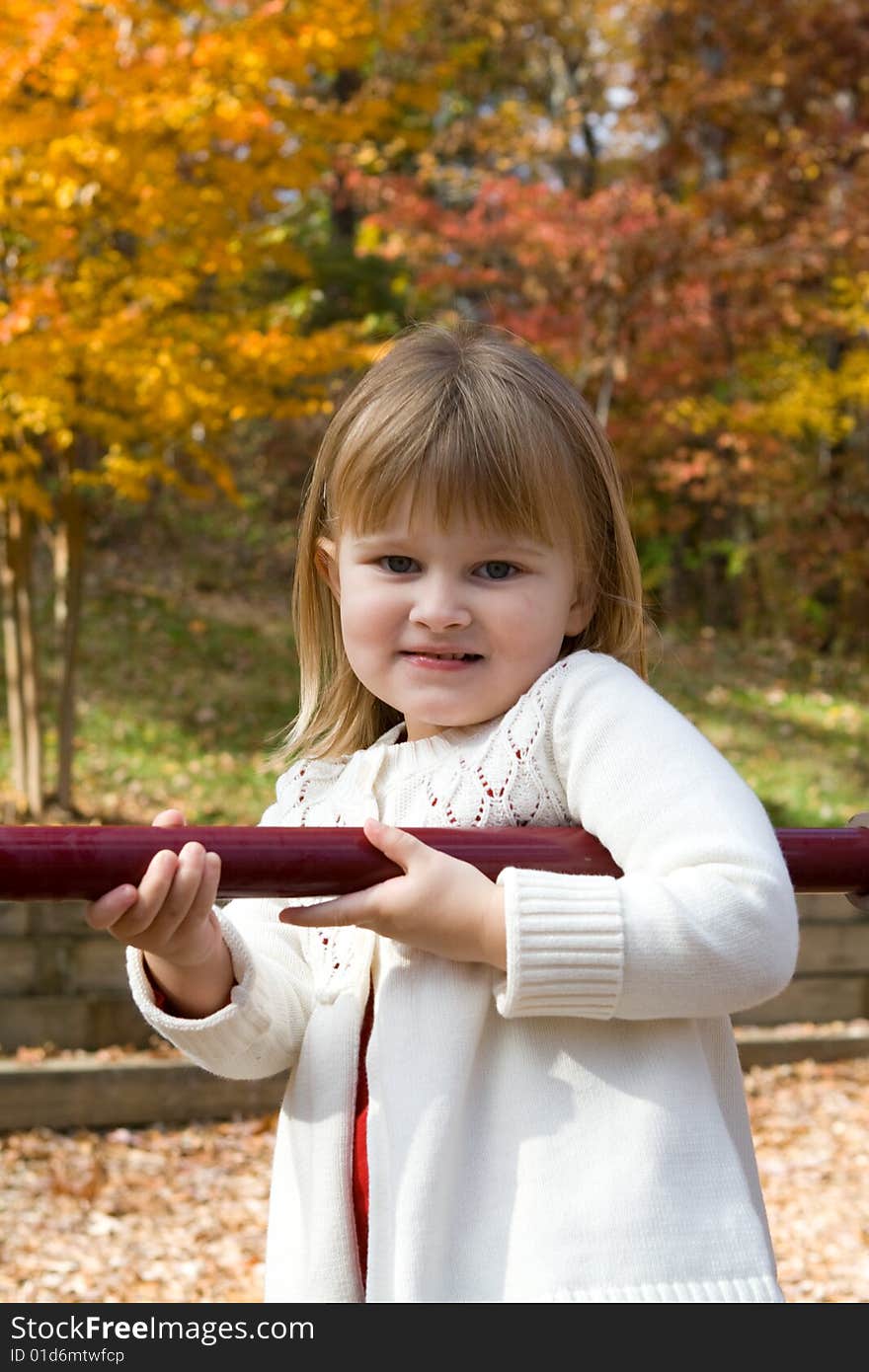 Little girl on the playground on an autumn day