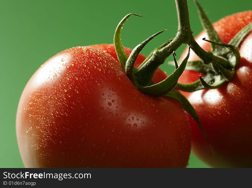 Red wet tomato macro over green background at studio. Red wet tomato macro over green background at studio