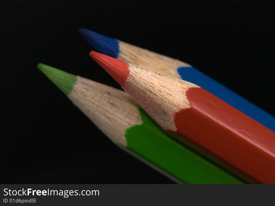 Red, green and blue pencils on dark background