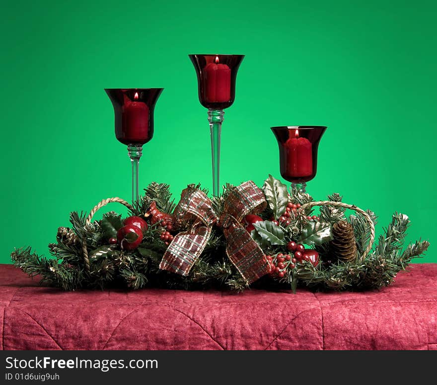 Three lit Christmas candles in a centerpiece. Three lit Christmas candles in a centerpiece.