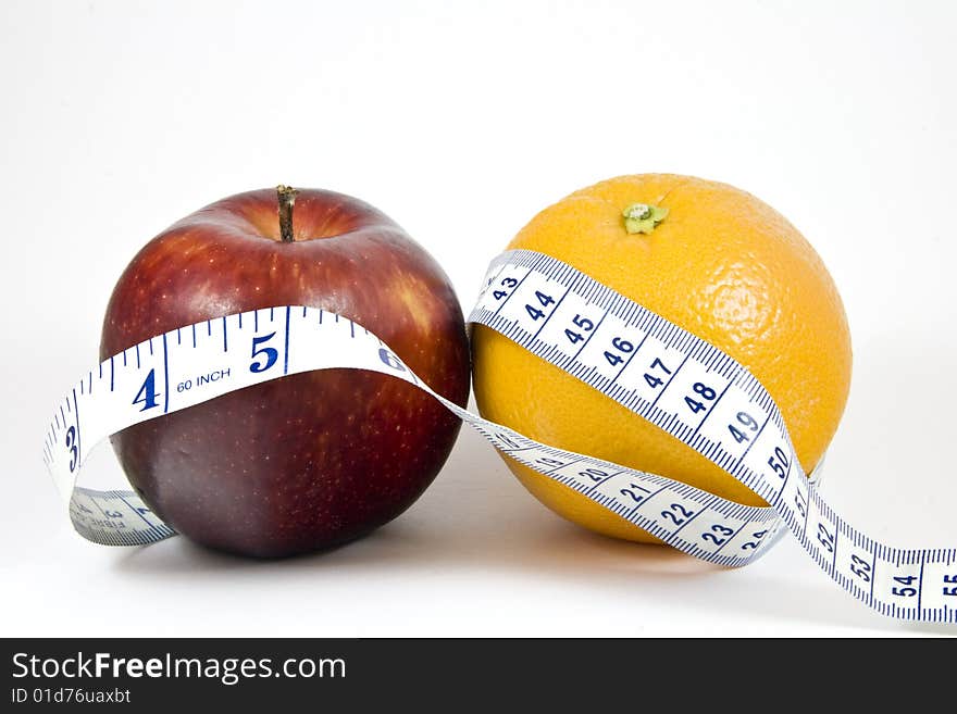 An apple and orange wrapped by a tape measure; isolated on white. An apple and orange wrapped by a tape measure; isolated on white