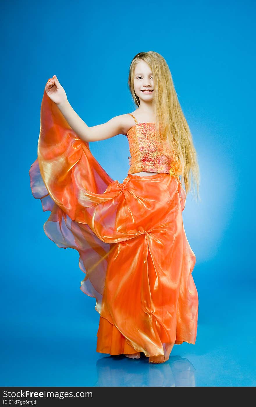 Smiling little girl in orange dress over blue background