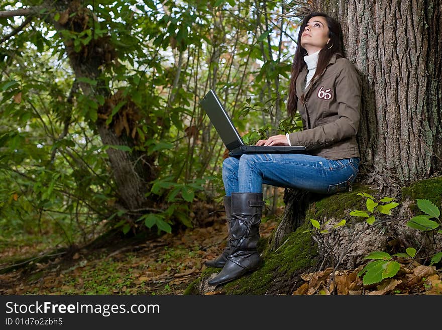 Young woman working with laptop on deep forest