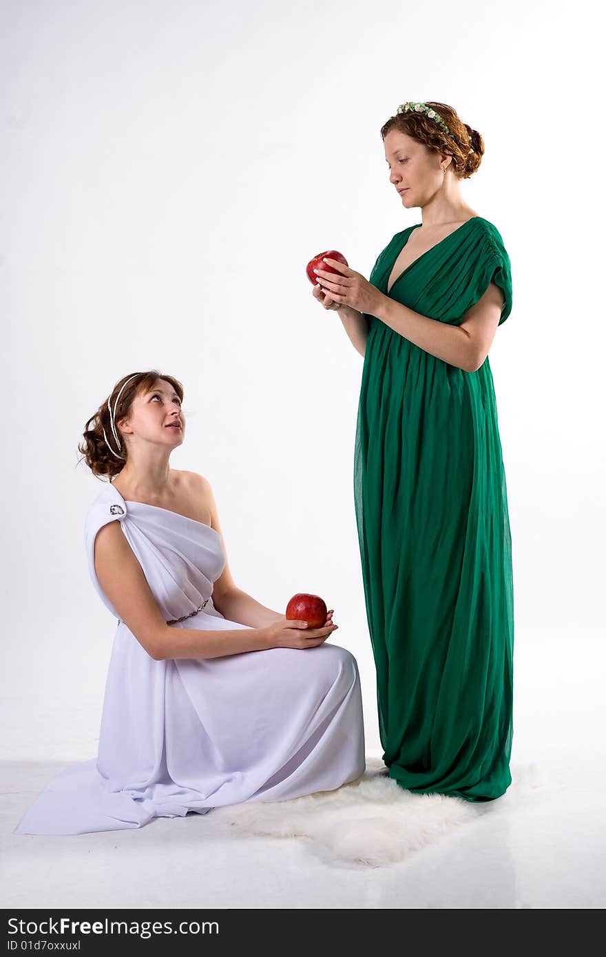 Two ladies in antique dress and two apples on white background. Two ladies in antique dress and two apples on white background